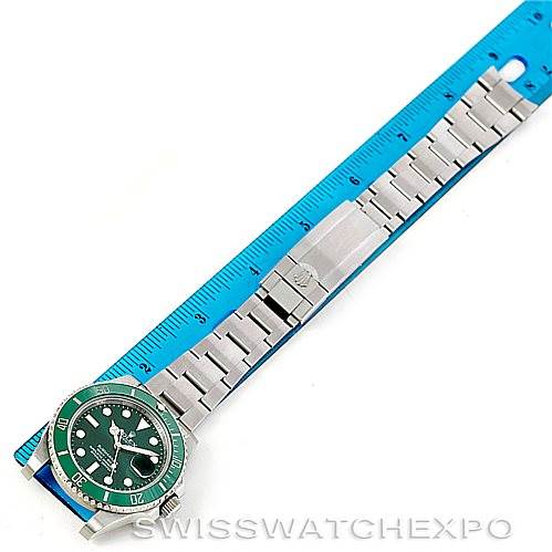 The image shows a top-down view of a Rolex Submariner 116610LV Men's Stainless Steel Green Dial 116610LV Men's Stainless Steel Green Dial watch with a metal bracelet, placed next to a blue measuring ruler.