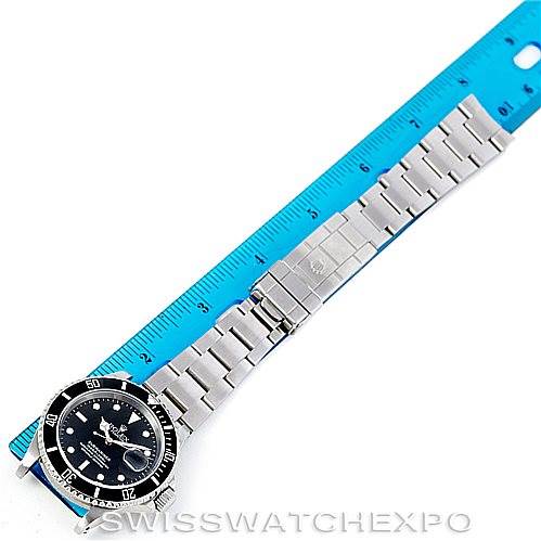 This image shows a Rolex Submariner 16610 Men's Stainless Steel Black Dial 16610 Men's Stainless Steel Black Dial watch laid flat with its face and bracelet extended next to a blue ruler for measurement.