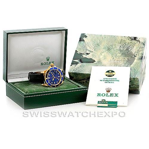 This image displays a Rolex Submariner 16808 Men's Yellow Gold Blue Dial 16808 Men's Yellow Gold Blue Dial watch in its box, accompanied by its instruction manual and warranty card.