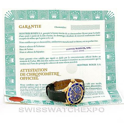 The image shows a Rolex Submariner 16808 Men's Yellow Gold Blue Dial 16808 Men's Yellow Gold Blue Dial watch angled to display its face and a warranty certificate behind it.