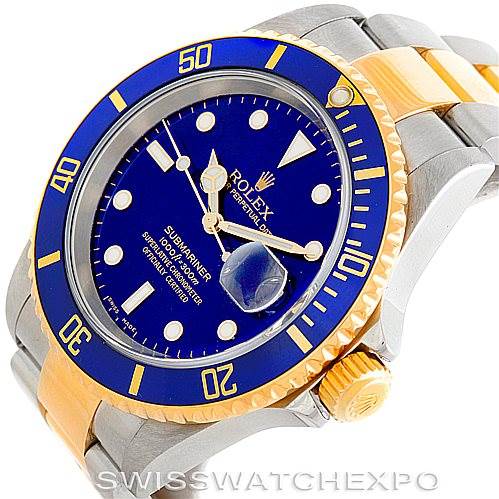The image shows a Rolex Submariner 16613 Men's Steel and Gold (two tone) Blue Dial 16613 Men's Steel and Gold (two tone) Blue Dial watch at an angled view, highlighting its blue dial, bezel, and two-tone band.