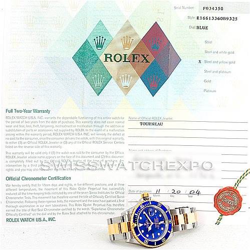 The image shows a Rolex Submariner 16613 Men's Steel and Gold (two tone) Blue Dial 16613 Men's Steel and Gold (two tone) Blue Dial watch and its official warranty and certification papers from a top-down angle.