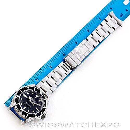 The image shows a Rolex Submariner 14060 Men's Stainless Steel Black Dial 14060 Men's Stainless Steel Black Dial watch laid next to a blue ruler, showcasing the watch face and stainless steel bracelet.