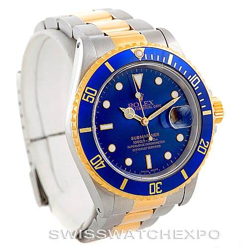 The image shows a Rolex Submariner 16613 Men's Steel and Gold (two tone) Blue Dial 16613 Men's Steel and Gold (two tone) Blue Dial watch at an angle emphasizing its blue dial, gold and steel bracelet, and bezel with a date magnifier.