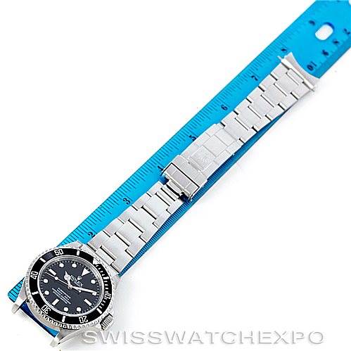 The image shows a Rolex Submariner 14060 Men's Stainless Steel Black Dial 14060 Men's Stainless Steel Black Dial watch laid flat next to a blue ruler, displaying its face and entire metal bracelet.