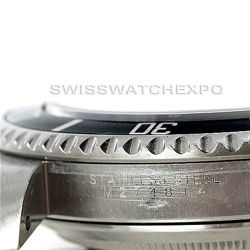 The image shows a close-up side angle of a Rolex Submariner 14060 Men's Stainless Steel Black Dial 14060 Men's Stainless Steel Black Dial's stainless steel case and bezel, displaying part of the serial number and "STAINLESS STEEL" engraving.