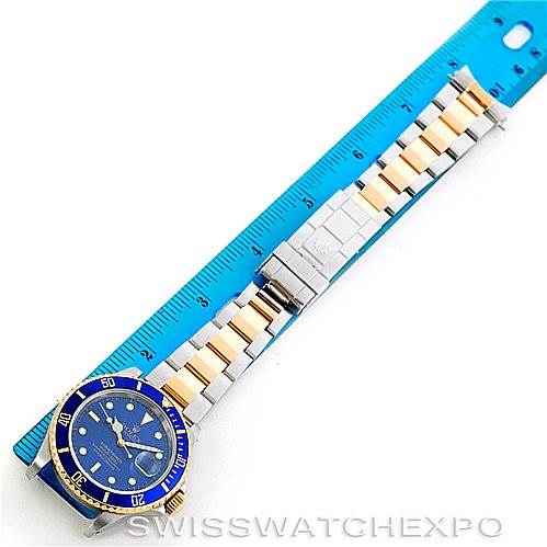 The image shows a Rolex Submariner 16613 Men
s Steel and Gold (two tone) Blue Dial 16613 Men
s Steel and Gold (two tone) Blue Dial watch laid flat, displaying the dial, bezel, and full length of the bracelet against a ruler.