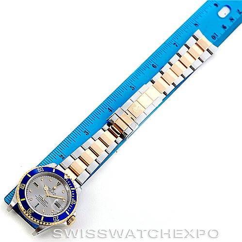 The image shows a Rolex Submariner 16613 Men's Steel and Gold (two tone) Grey Dial 16613 Men's Steel and Gold (two tone) Grey Dial watch laid flat against a ruler, highlighting the watch face, bezel, and bracelet.