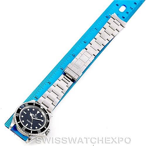 The image shows a top-down view of the Rolex Submariner 14060 Men
s Stainless Steel Black Dial 14060 Men
s Stainless Steel Black Dial watch laid next to a blue ruler, displaying the entire band and watch face.