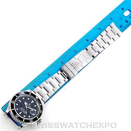 The image shows a top-down view of a Rolex Submariner 16610 Men
s Stainless Steel Black Dial 16610 Men
s Stainless Steel Black Dial watch alongside a blue ruler.