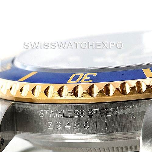 The image shows a close-up of the bezel and outer edge of a Rolex Submariner 16613 Men
s Steel and Gold (two tone) Blue Dial 16613 Men
s Steel and Gold (two tone) Blue Dial watch, highlighting the serial number and "stainless steel" engraving.