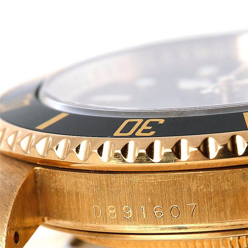The image shows a close-up side view of the bezel, case, and part of the serial number of a Rolex Submariner 16618 Men
s Yellow Gold Black Dial 16618 Men
s Yellow Gold Black Dial watch.