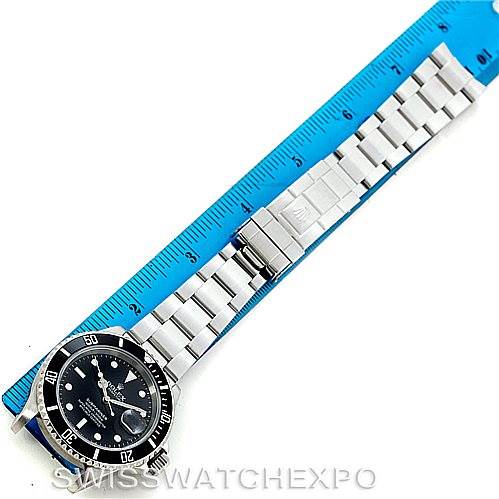 The image shows a top view of a Rolex Submariner 16610 Men
s Stainless Steel Black Dial 16610 Men
s Stainless Steel Black Dial watch laid flat next to a blue ruler.