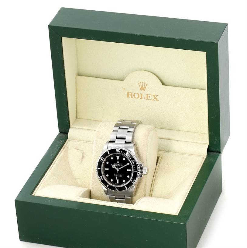The image shows a Rolex Submariner 14060 Men
s Stainless Steel Black Dial 14060 Men
s Stainless Steel Black Dial watch placed upright in an open, green and beige Rolex box, viewed from the front.