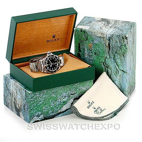 The image shows a Rolex Submariner 14060 Men
s Stainless Steel Black Dial 14060 Men
s Stainless Steel Black Dial watch at an angled view inside an open green and wooden Rolex box, with additional packaging and a cleaning cloth.