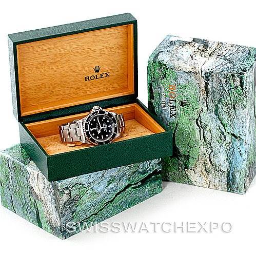 This image shows a Rolex Submariner 16610 Men
s Stainless Steel Black Dial 16610 Men
s Stainless Steel Black Dial watch placed in an open green and wooden box, with additional green marble-patterned exterior boxes beside it.