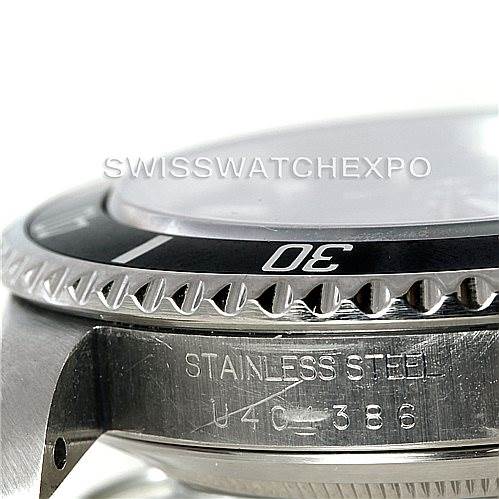 The image shows a close-up view of a Rolex Submariner 14060 Men
s Stainless Steel Black Dial 14060 Men
s Stainless Steel Black Dial watch, featuring the bezel, part of the crystal, and the stainless steel case.