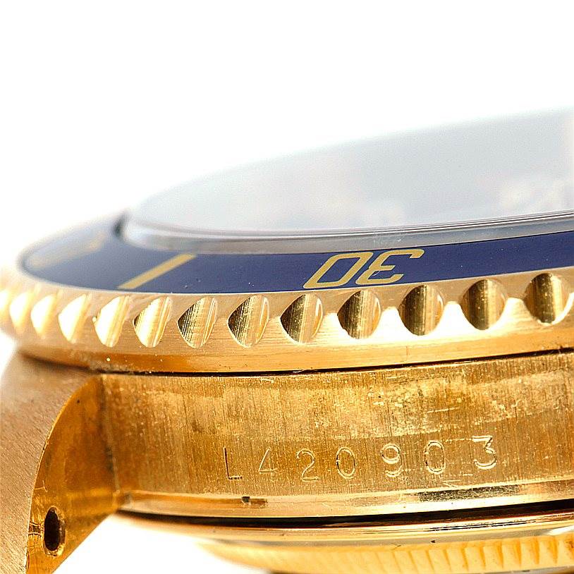 This close-up image of the Rolex Submariner 16618 Men
s Yellow Gold Blue Dial 16618 Men
s Yellow Gold Blue Dial watch shows the bezel, case, and part of the serial number.