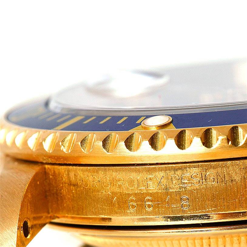 The image shows a close-up of the case side and bezel of a Rolex Submariner 16618 Men
s Yellow Gold Blue Dial 16618 Men
s Yellow Gold Blue Dial, emphasizing the engraving, crown guard, and bezel markings.