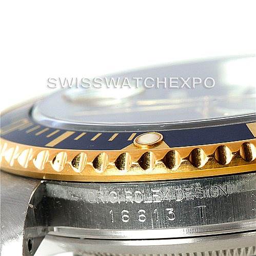 This close-up angle of a Rolex Submariner 16613 Men
s Steel and Gold (two tone) Blue Dial 16613 Men
s Steel and Gold (two tone) Blue Dial showcases the bezel, part of the crystal, and the "ORIG ROLEX DESIGN" engraving with the serial number.