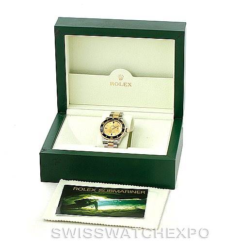 The image shows a Rolex Submariner 16613 Men's Steel and Gold (two tone) Champagne Dial 16613 Men's Steel and Gold (two tone) Champagne Dial watch in its open green display box, alongside a cleaning cloth and an information booklet.