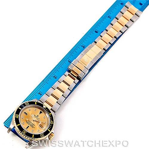 The image shows a top view of a Rolex Submariner 16613 Men's Steel and Gold (two tone) Champagne Dial 16613 Men's Steel and Gold (two tone) Champagne Dial watch, including the dial, bezel, and bracelet, alongside a ruler for size reference.