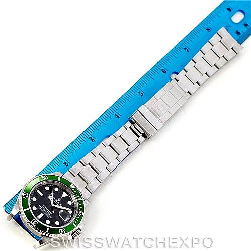 The Rolex Submariner 16610V Men
s Stainless Steel Black Dial 16610V Men
s Stainless Steel Black Dial watch is shown from a top-down angle, with the dial, bezel, and full bracelet visible next to a blue ruler for scale.