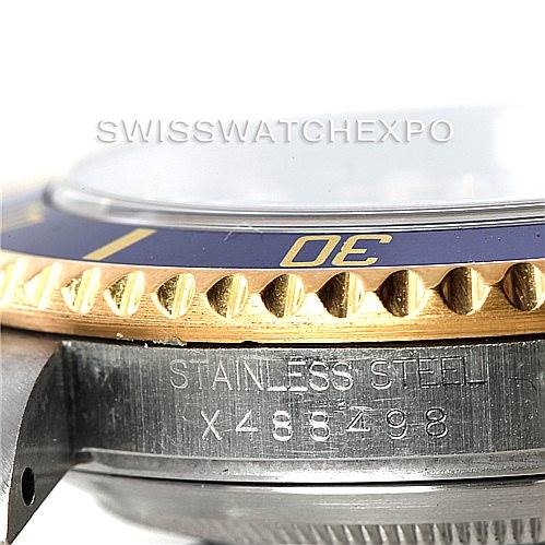 This close-up image of a Rolex Submariner 16613 Men's Steel and Gold (two tone) Blue Dial 16613 Men's Steel and Gold (two tone) Blue Dial shows a partial view of the bezel, crystal, and case with the serial number engraved on the stainless steel casing.