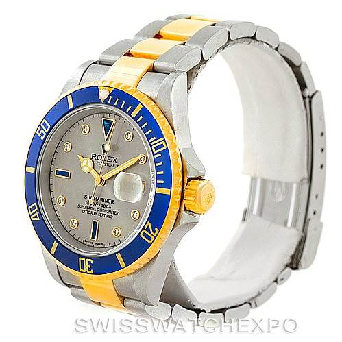 The image shows a Rolex Submariner 16613 Men's Steel and Gold (two tone) Grey Dial 16613 Men's Steel and Gold (two tone) Grey Dial watch at a three-quarter angle, highlighting its blue bezel, gold and silver bracelet, and grey dial.