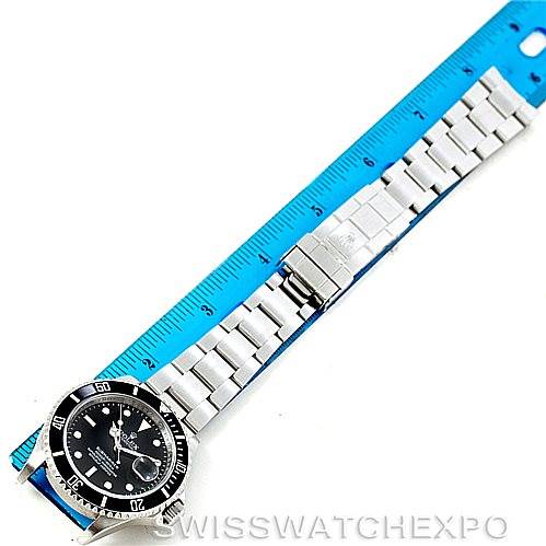 The Rolex Submariner 16610 Men
s Stainless Steel Black Dial 16610 Men
s Stainless Steel Black Dial watch is shown from a top-down angle, displaying its face and full metal bracelet laid flat with a ruler alongside.