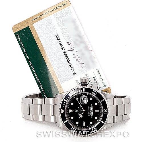 The image shows a Rolex Submariner 16610 Men
s Stainless Steel Black Dial 16610 Men
s Stainless Steel Black Dial watch from the front, including its bracelet and a warranty card in the background.