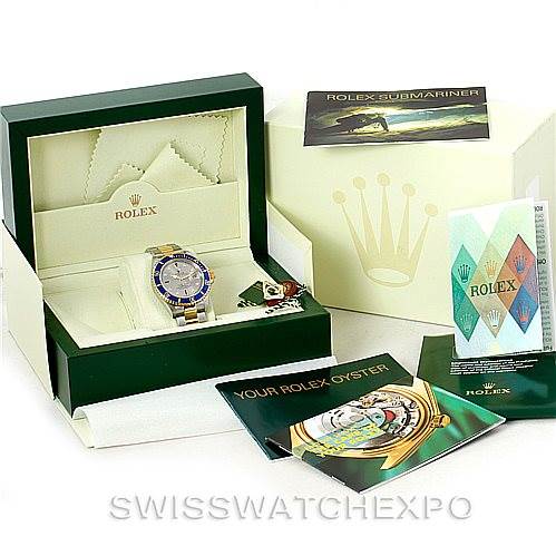The image shows a Rolex Submariner 16613 Men
s Steel and Gold (two tone) Grey Dial 16613 Men
s Steel and Gold (two tone) Grey Dial watch in its open box, with accompanying manuals, tags, and warranty cards.