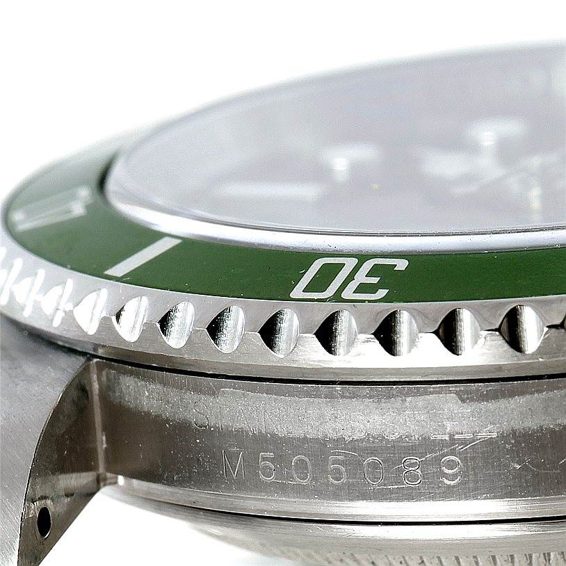The image shows a close-up of the bezel, crystal, and part of the case with engraving on a Rolex Submariner 16610V Men
s Stainless Steel Black Dial 16610V Men
s Stainless Steel Black Dial watch.