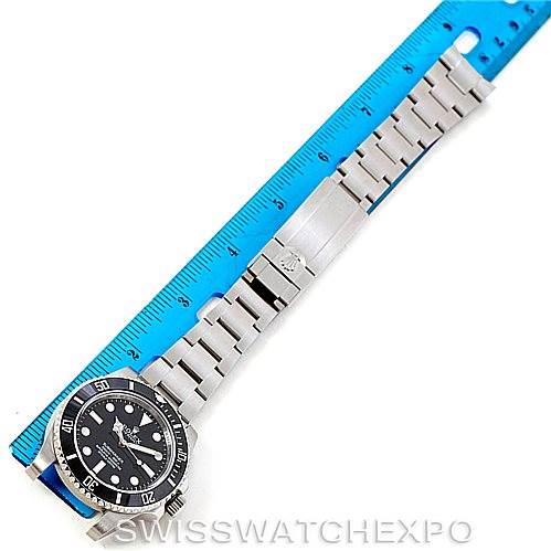 The image showcases a Rolex Submariner 114060 Men
s Stainless Steel Black Dial 114060 Men
s Stainless Steel Black Dial watch laid flat next to a blue ruler, highlighting the full length of the bracelet and face.