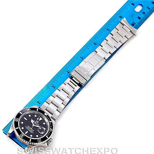 The image shows a full view of the Rolex Submariner 16610 Men
s Stainless Steel Black Dial 16610 Men
s Stainless Steel Black Dial watch laid flat next to a blue ruler for size comparison.