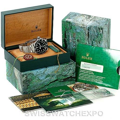 The image shows a Rolex Submariner 16610 Men
s Stainless Steel Black Dial 16610 Men
s Stainless Steel Black Dial watch with its box, warranty card, and various accessories from a top-down angle.