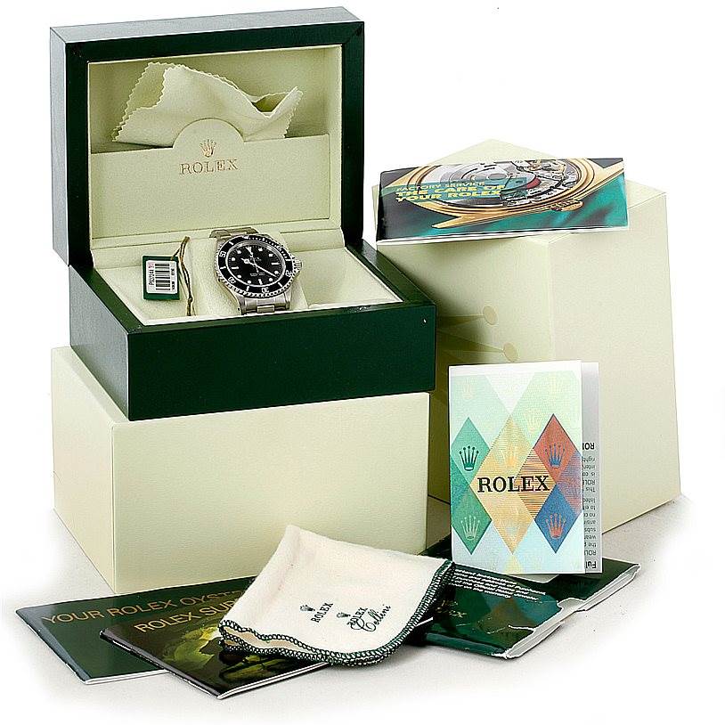 The image shows a Rolex Submariner 14060 Men
s Stainless Steel Black Dial 14060 Men
s Stainless Steel Black Dial watch inside its box, with manuals, tags, and a cleaning cloth.