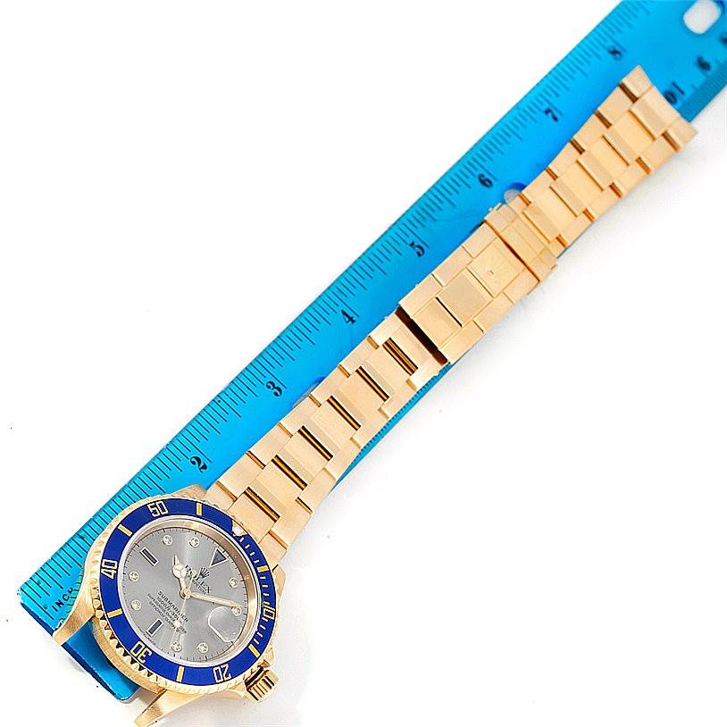 This image shows a laid-flat Rolex Submariner 16618 Men's Yellow Gold Grey Dial 16618 Men's Yellow Gold Grey Dial watch with the face, bezel, and bracelet clearly visible, aligned next to a ruler.