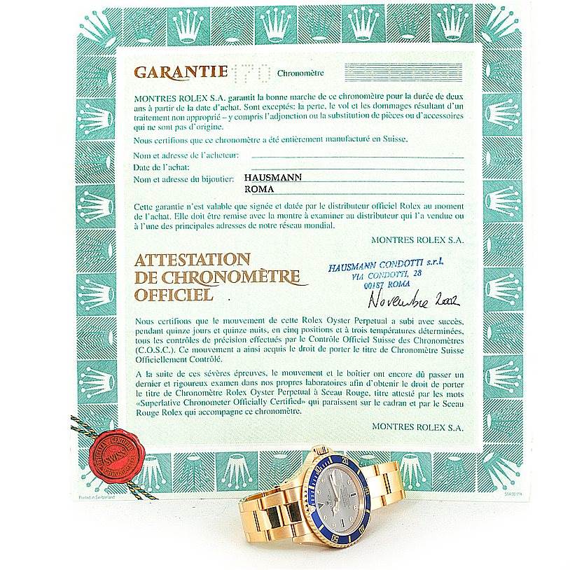 The image shows a Rolex Submariner 16618 Men's Yellow Gold Grey Dial 16618 Men's Yellow Gold Grey Dial watch angled slightly to the side, along with its warranty and chronometer certification papers.