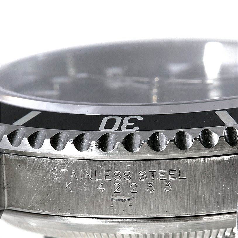 The photo shows a close-up of the bezel, crystal, and engraved side of the case of a Rolex Submariner 14060 Men
s Stainless Steel Black Dial 14060 Men
s Stainless Steel Black Dial watch.