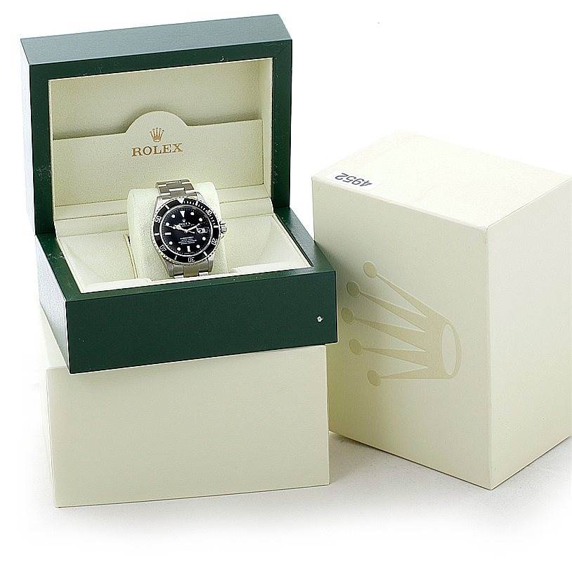 The Rolex Submariner 16610 Men
s Stainless Steel Black Dial 16610 Men
s Stainless Steel Black Dial watch is shown front-facing in its open green and cream case, with the outer packaging visible beside it.