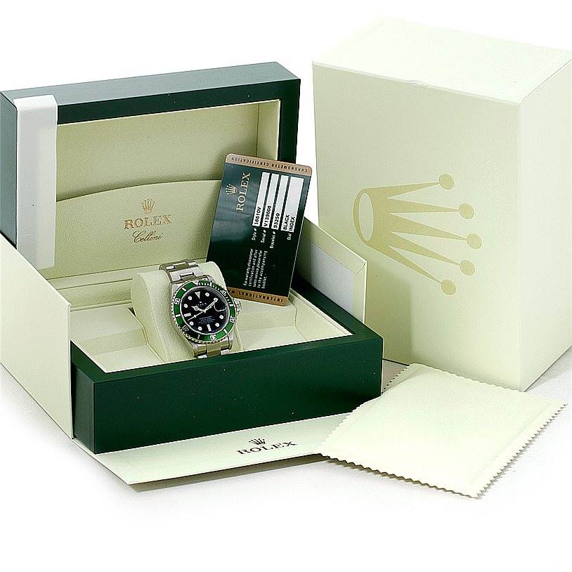 The image shows a Rolex Submariner 16610 Men
s Stainless Steel Black Dial 16610 Men
s Stainless Steel Black Dial watch in its box, with accompanying documentation and a cleaning cloth.