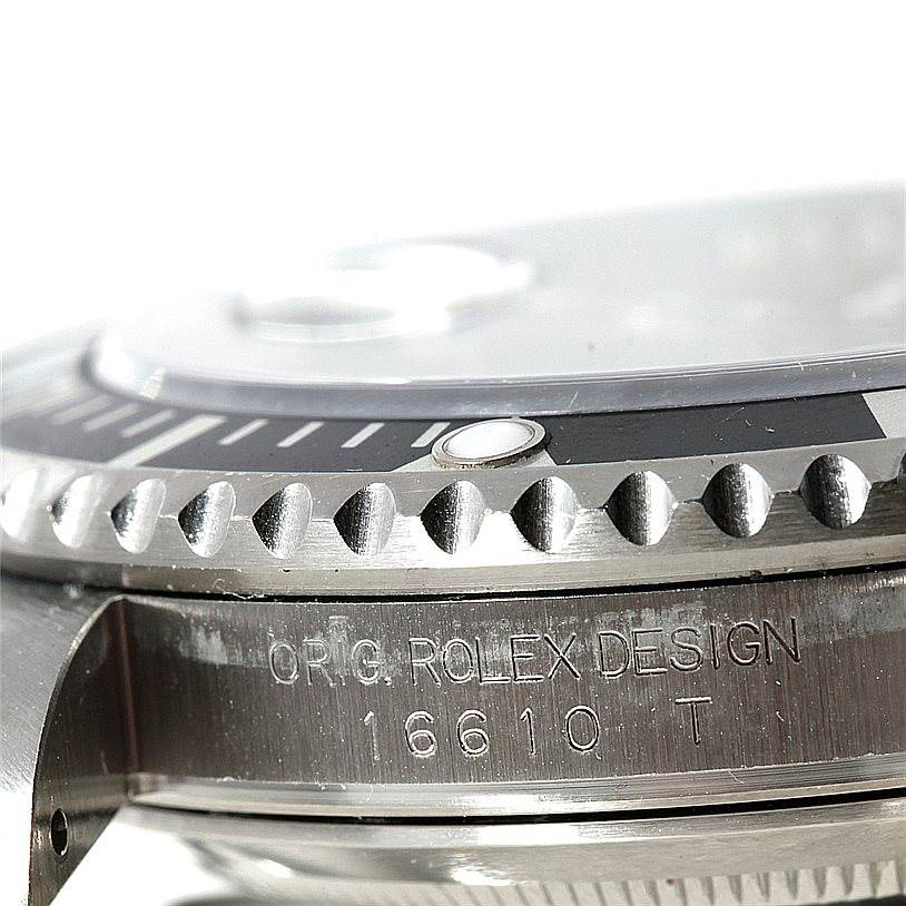 The image shows a close-up of the bezel and the case side of a Rolex Submariner 16610 Men
s Stainless Steel Black Dial 16610 Men
s Stainless Steel Black Dial, featuring the engraved words and model number "16610 T."