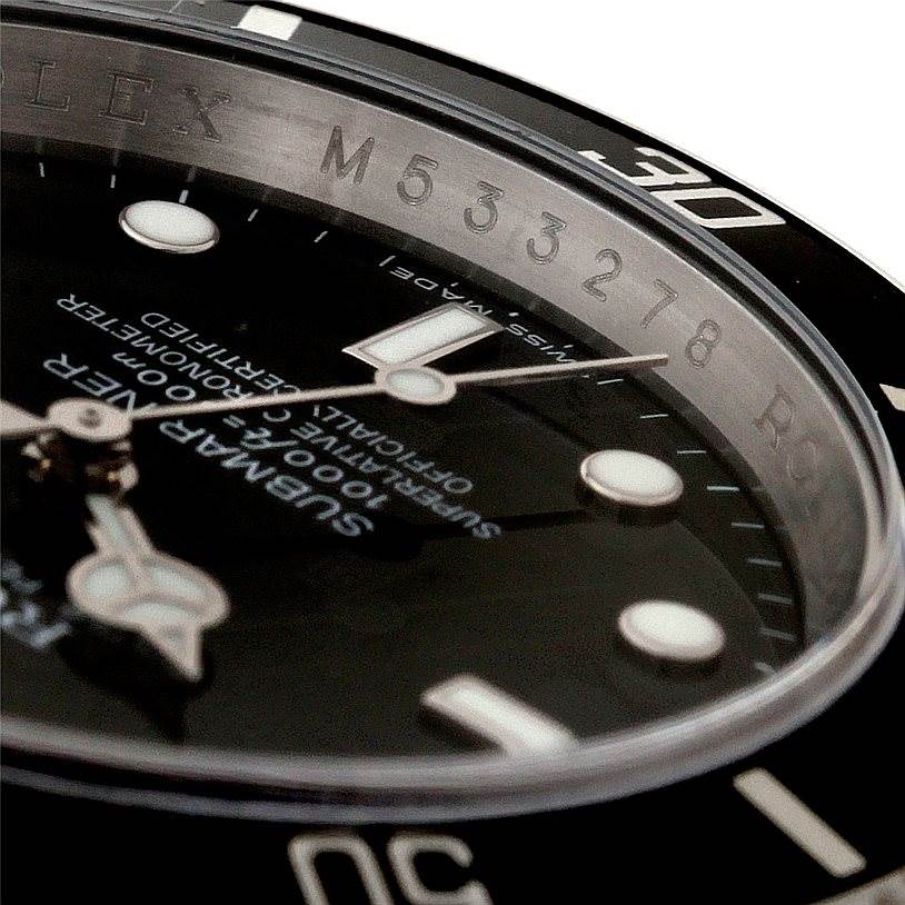 The image shows a close-up angle of a Rolex Submariner 16610 Men
s Stainless Steel Black Dial 16610 Men
s Stainless Steel Black Dial watch dial and bezel, highlighting the engraved serial number and hour markers.