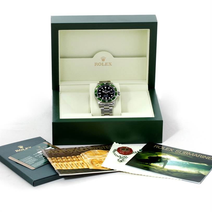 The Rolex Submariner 16610 Men
s Stainless Steel Black Dial 16610 Men
s Stainless Steel Black Dial watch is shown front-facing in its box with accompanying booklets and accessories laid out in front.