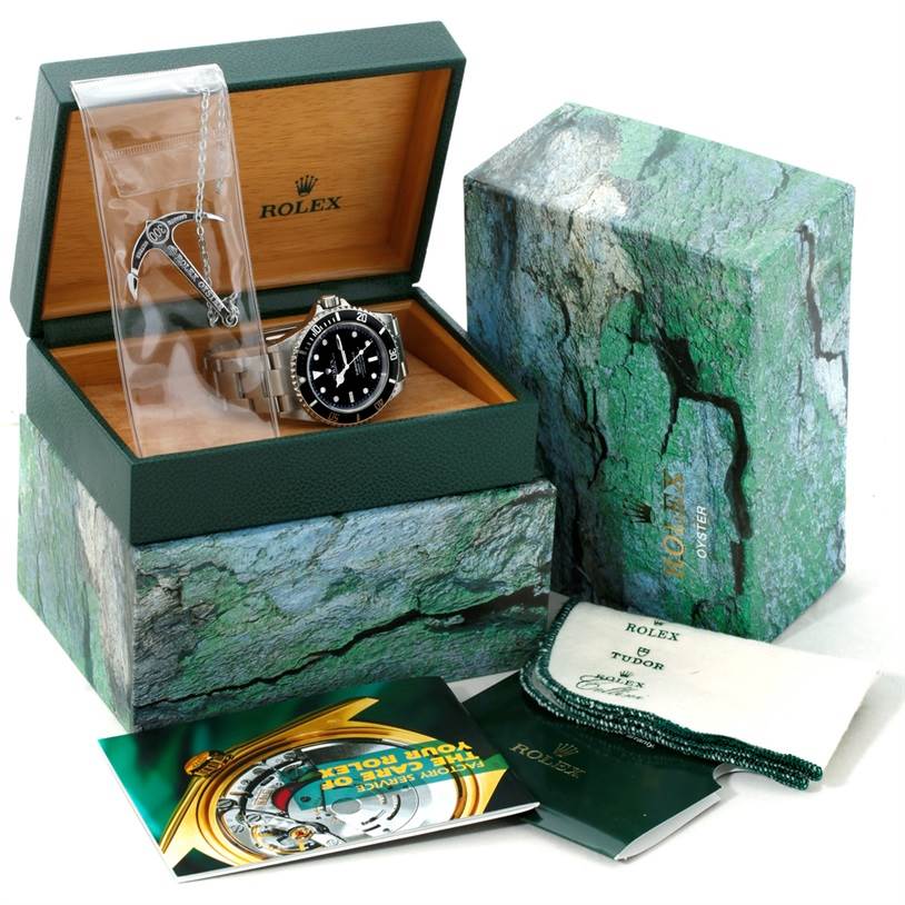 The image shows a Rolex Submariner 16610 Men
s Stainless Steel Black Dial 16610 Men
s Stainless Steel Black Dial watch inside a Rolex box with booklets and a cleaning cloth next to it.