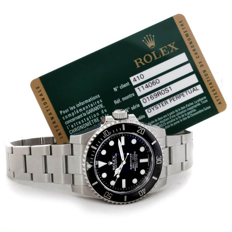 The image shows a Rolex Submariner 114060 Men
s Stainless Steel Black Dial 114060 Men
s Stainless Steel Black Dial watch laid flat with its certification card positioned behind it.
