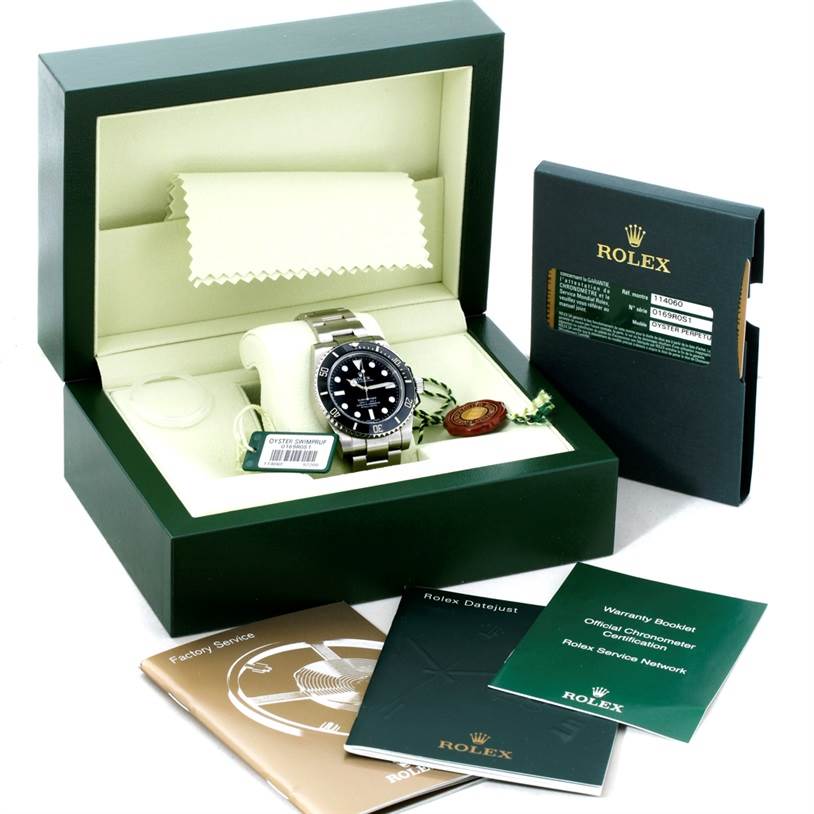 The image shows a Rolex Submariner 114060 Men
s Stainless Steel Black Dial 114060 Men
s Stainless Steel Black Dial watch in its box, along with documentation, a warranty booklet, and a green Rolex tag.