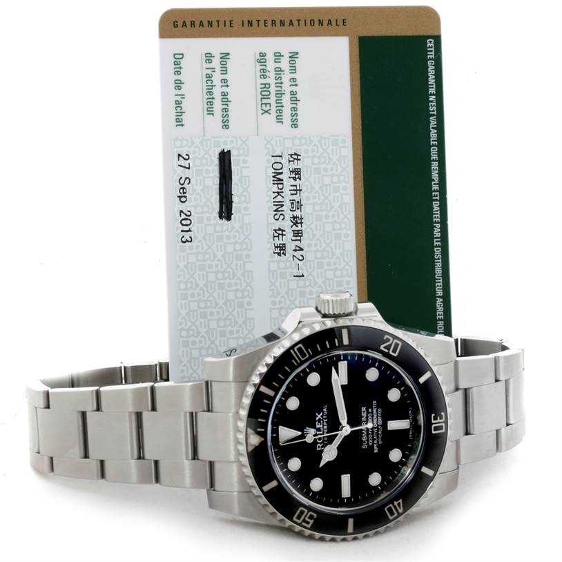 The image shows a Rolex Submariner 114060 Men
s Stainless Steel Black Dial 114060 Men
s Stainless Steel Black Dial watch with its face, bezel, bracelet, and a warranty card in the background.