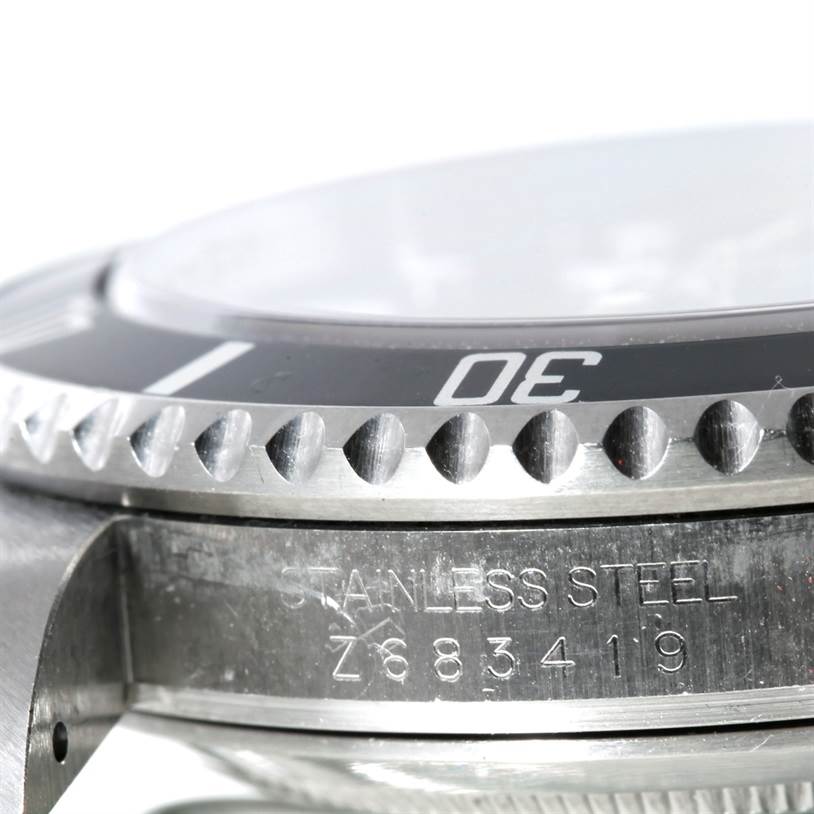 The image shows a close-up of the side of a Rolex Submariner 16610 Men
s Stainless Steel Black Dial 16610 Men
s Stainless Steel Black Dial watch, focusing on its bezel, crystal, and stainless steel engravings.